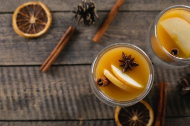 Ahşap masa arkasında elma suyu olan iki bardak. Sıcak kış içeceği. Üst görünüm, alanı kopyala.