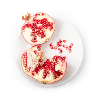 Beyaz tabakta kırık nar meyvesi var. Kırmızı punica granatum, granatum veya garnet izole üst görünüm