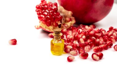 Nar yağı ve dağınık nar tohumları beyaz arka planda izole edilmiş. Kırmızı punica granatum esaslı yağ, tentür, özüt, infüzyon, uçucu yağlar, özü