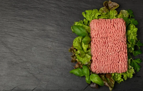 Turkey mince meat mockup. Ground fillet on black background with copy space, uncooked turkey mincemeat flat lay, raw forcemeat, fresh farce meat portion with greens top view