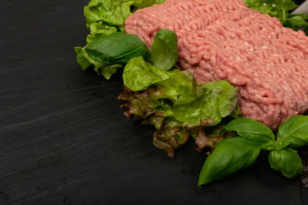 Turkey mince meat mockup. Ground fillet on black background with copy space, uncooked turkey mincemeat flat lay, raw forcemeat, fresh farce meat portion with greens