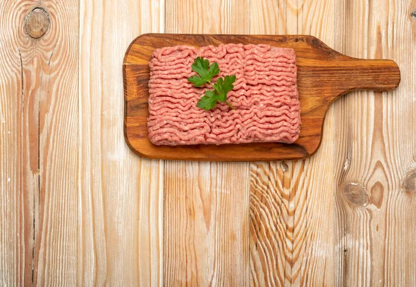 Turkey mince meat mockup. Ground fillet on wood background with copy space, uncooked turkey mincemeat flat lay, raw forcemeat, fresh farce meat portion with greens top view