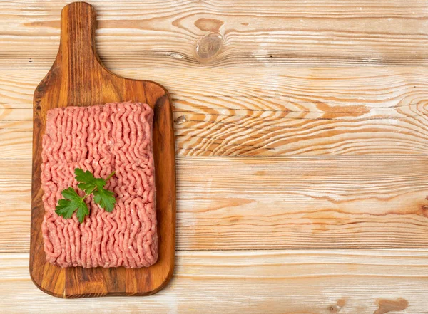 Turkey mince meat mockup. Ground fillet on wood background with copy space, uncooked turkey mincemeat flat lay, raw forcemeat, fresh farce meat portion with greens top view