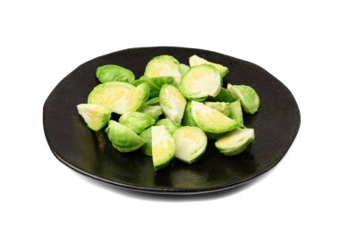 Brüksel lahanası izole edilmiş. Siyah tabakta Brassica oleracea lahanası, beyaz arka planda yenilebilir tomurcukları kes.