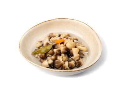 İzole edilmiş saman mantarları. Terbiye edilmiş mantar çorbası, volvariella turşusu, sağIık aperatifi, beyaz arka planda agarik koruma, kil kasede tuzlanmış mantar.