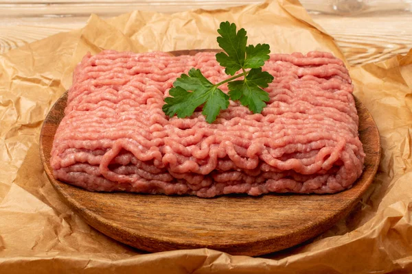 Turkey minced meat. Ground fillet on wood plate background, uncooked turkey mincemeat, raw forcemeat, fresh farce meat portion with greens