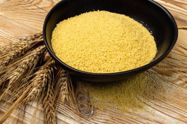 Siyah kasede kuskus yığını. Kuru yastık, çiğ kuskus, ahşap arka planda pişmemiş kuskus veya irmik granüller.