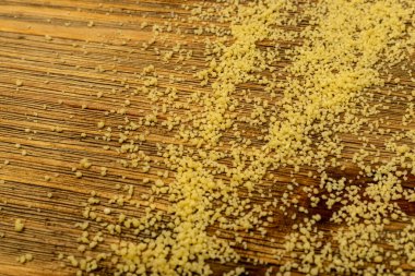 Kuskus dokusu arkaplan üstü görünümü. Kuru yastık, çiğ kuskus, pişmemiş kuskus veya ahşap zemine saçılmış irin tanecikleri.