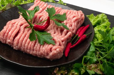 Kıymalı domuz eti yakın plan. Taze fileto, pişmemiş domuz kıyması, çiğ et, yeşil soslu komedi kıymalı et porsiyonu ve siyah arka planda kırmızı biber.