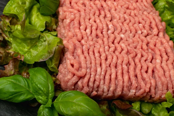 Turkey mince meat texture background. Ground fresh fillet textured pattern, uncooked turkey mincemeat, raw forcemeat, farce meat with greens top view