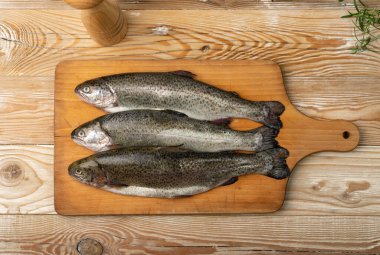 Tahta tabakta çiğ alabalık. Taze cani, üç çelik başlı balık, gökkuşağı alabalığı, trutta, fario, Oncorhynchus mykiss, ahşap arka planda tatlı su alabalıkları.