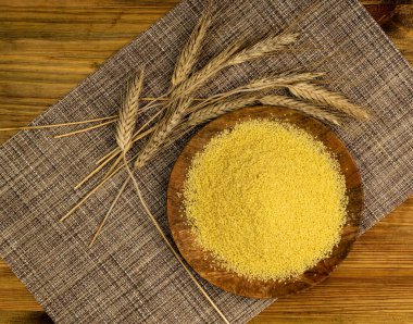 Tahta tepsi manzaralı kuskus yığını. Kuru yastık, çiğ kuskus, ahşap arka planda pişmemiş kuskus veya irmik granüller.