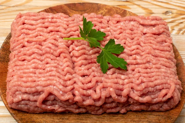 Turkey minced meat. Ground fillet on wood background, uncooked turkey mincemeat, raw forcemeat, fresh farce meat portion with greens