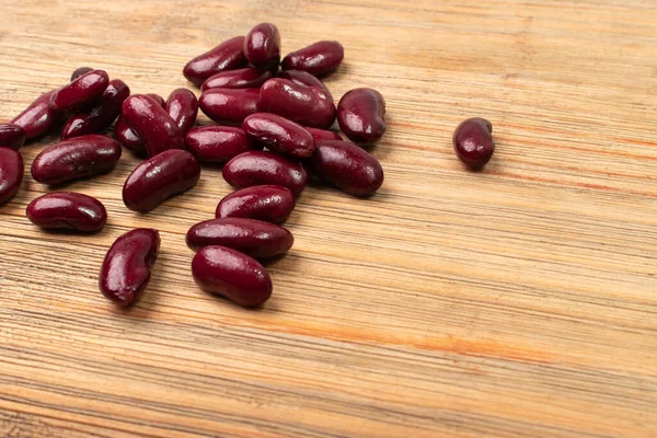 Red kidney beans on wood background. Cooked bean pile, baked legume, canned red beans, rajma, Phaseolus vulgaris, leguminous salad ingredient