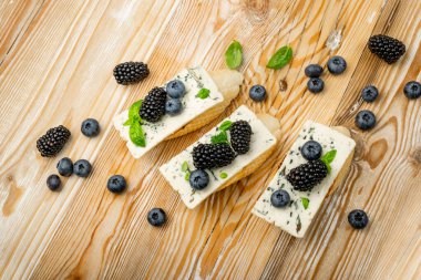 Ekmeğin üstünde mavi peynir. Böğürtlenli ve ballı Gorgonzola, ricottalı bruschetta, yaban mersini ve böğürtlenli bruschetta, ahşap arka plan manzaralı Fransız tostu.