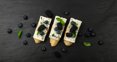 Ekmeğin üstünde mavi peynir. Böğürtlen ve bal ile Gorgonzola, ricotta ile bruschetta, yaban mersini ve böğürtlen, ahşap arka planda Fransız tostu.