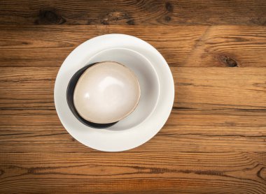 Kırsal ahşap arka planda kase yığını. Yığınlanmış tabaklar, çeşitli kaseler, ahşap masa zemininde ahşap masa örtüsü ve fotokopi alanı manzaralı seramik tabaklar.