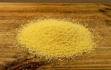 Couscous pile closeup. Dry cuscus, raw kuskus, uncooked cous cous or semolina granules on wooden rustic background