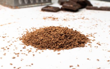 Izgara çikolata izole. Ezilmiş çikolata parçacıkları, kırıntı yığınları, kar taneleri, tatlı parçacıkları beyaz arka plandaki süslemeler için çikolata parçacıkları