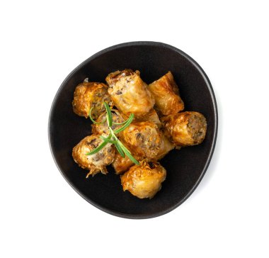 Spring rolls isolated. Rollos primavera pieces, fried rollito, arrollado, lumpia cuts, popiah, nem, sajgonki or fried dim sim pile in black bowl on white background