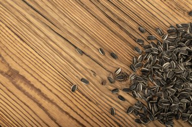 Dağıtılmış ayçekirdeği dokusu arka planı. Çiğ ayçiçeği tohumu deseni, ahşap masa üzerindeki güneş çiçeği tanecikleri, yenilebilir çizgili taze çekirdekler düz yerde, fotokopi alanı ile üst manzara