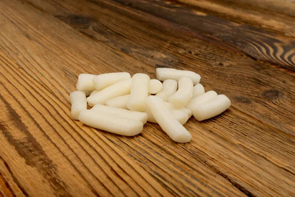 Ahşap masanın üzerinde sade bir içki. Topokki Kore yemeği, çiğ pirinç keki çubukları, tukbokki, ahşap arka planda pişmemiş tteokbokki.