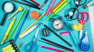 School accessories completely fill frame and move making empty blue background