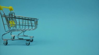 Shopping trolley with books is moving on a blue background. Stop motion