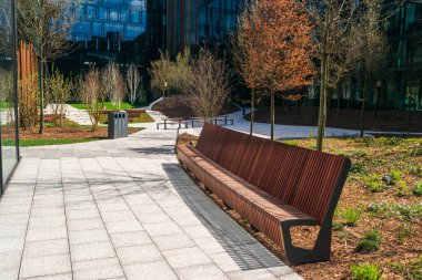 Parkın yeni modern bankı. Şehir mimarisi, ahşap bahçe koltuğu, şehir mobilyası, boş tahta koltuk, dinlenme alanında rahat bank.