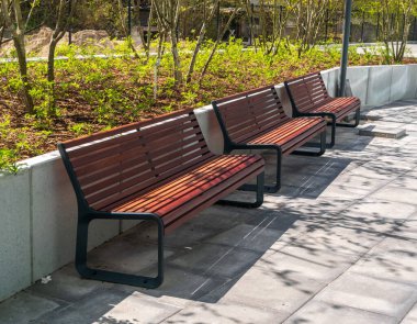 Parkın yeni modern bankı. Şehir mimarisi, ahşap banklar, açık sandalye, şehir mobilyası, boş tahta koltuk, dinlenme alanında rahat bank