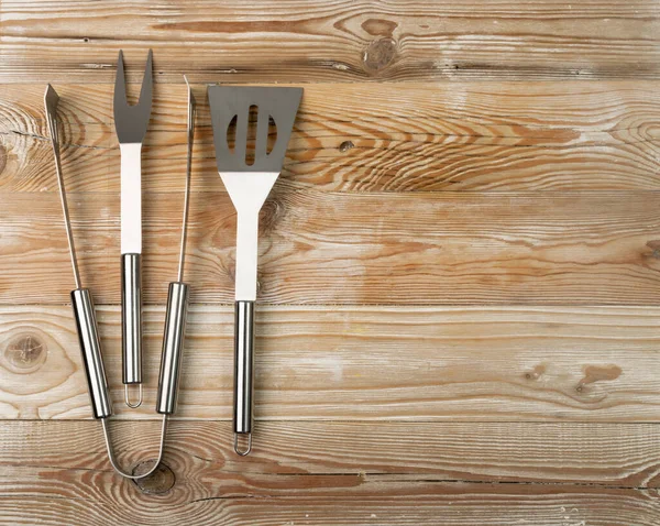 Metal kitchen thongs on wooden board Stock Photo - Alamy