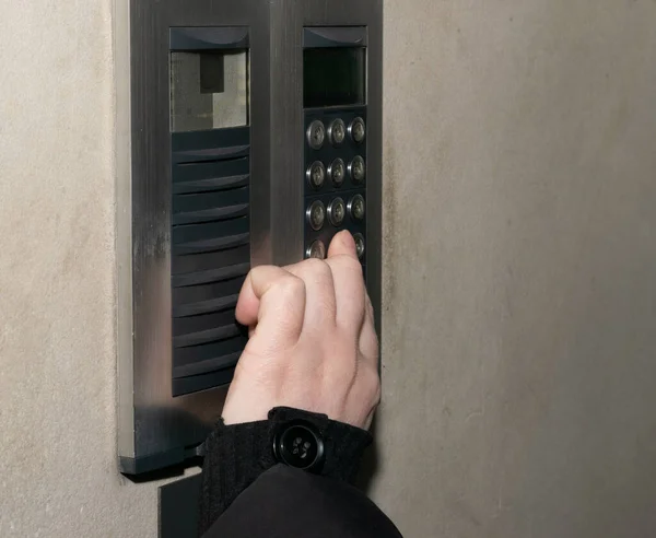 Secure home system. Hand pressing on intercom keypad, using door phone, doorphone, entryphone, videophone call