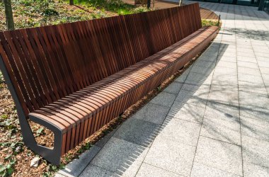 Parkın yeni modern bankı. Şehir mimarisi, ahşap bahçe koltuğu, şehir mobilyası, boş tahta koltuk, dinlenme alanında rahat bank.