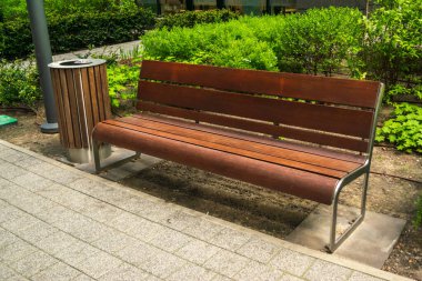Wooden garbage bin and bench in park. Outdoor city architecture, wooden benches, outdoor chair, empty plank seat, comfortable bench in recreation area