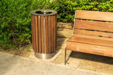 Wooden garbage bin, trash can and bench in park. Old wood waste bin for mixed trash and not recyclable waste