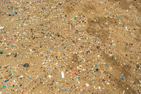 Microplastics on sand beach. Micro plastics garbage, tiny trash pieces, microplastic waste, dirty shore, small plastic parts on the coast of Greece, water pollution concept