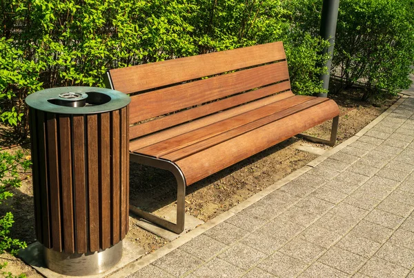Wooden garbage bin and bench in park. Outdoor city architecture, wooden benches, outdoor chair, empty plank seat, comfortable bench in recreation area