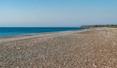 Desert pebble beach texture background. Blue ocean water, rocky shore pattern, summer mockup with copy space, stone shoreline, vacation concept