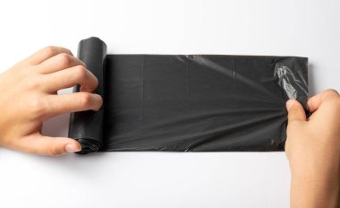 Hands holding garbage bag isolated. Trash package roll, new rolled plastic bin bags, black polyethylene waste container on white background