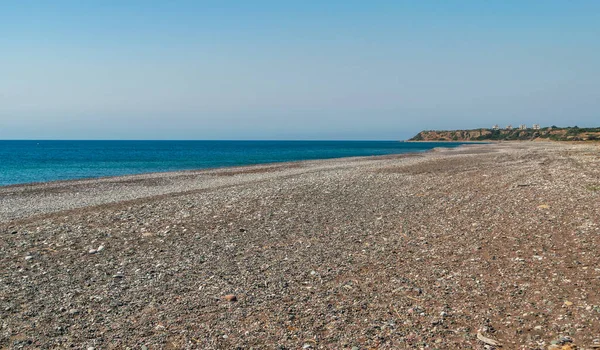 Desert pebble beach texture background. Blue ocean water, rocky shore pattern, summer mockup with copy space, stone shoreline, vacation concept