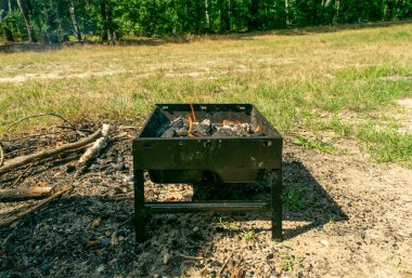 Small grill, portable barbecue, bbq with flame and smoke. Mini barbecue for outdoor recreation, tailgating, entertaining, beach parties