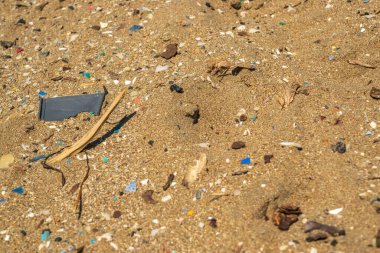 Microplastics on sand beach. Micro plastics garbage, tiny trash pieces, microplastic waste, dirty shore, small plastic parts on the coast of Greece, water pollution concept