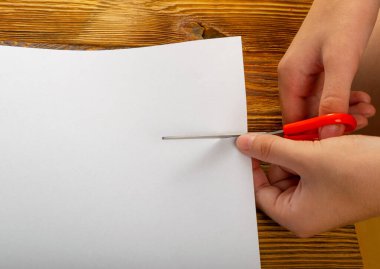 Makas kesme kağıdı. Makasla el beyaz kağıt parçasının üst görünümünü keser