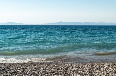 Sea waves on pebble beach texture background. Transparent ocean water, rocky shore pattern, summer mockup with copy space, stone shoreline, vacation concept