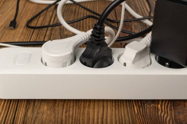 Tahta arka planda bir sürü fişi olan güç şeridi. USB kablosu, elektrik kablosu şarj etme, ev soketi, güç uzatma, uzatma kablosu kapatma
