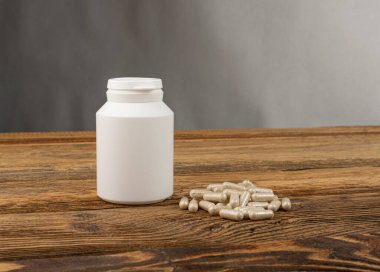 Bitkisel ilaç modeli. Ahşap arka planda ilaç şişesi, geleneksel ilaç kapsülleri, takviye, bitki kapsülü, bitkisel vitaminler, fotokopi alanı olan biyolojik destek şişesi.