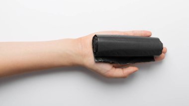Hands holding garbage bag isolated. Trash package roll, new rolled plastic bin bags, black polyethylene waste container on white background