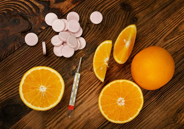 医療用温度計付きの発酵オレンジ錠剤 木の背景に固定果物の錠剤の山 病気の予防の概念 ピンクオレンジの果糖ビタミンサプリメント — ストック写真