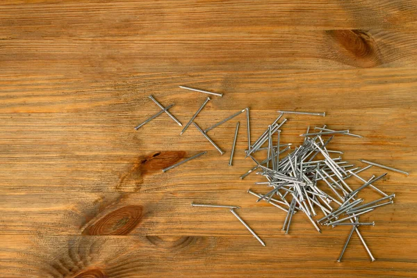 木製の机の上に金属釘杭 木板の鋼釘 茶色の木の背景に建設ハードウェア Top View — ストック写真