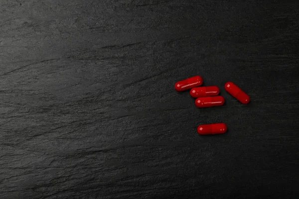 Red pills on black plate. Capsule set , analgesic, painkiller drugs, sedative pill collection, medicine capsules group